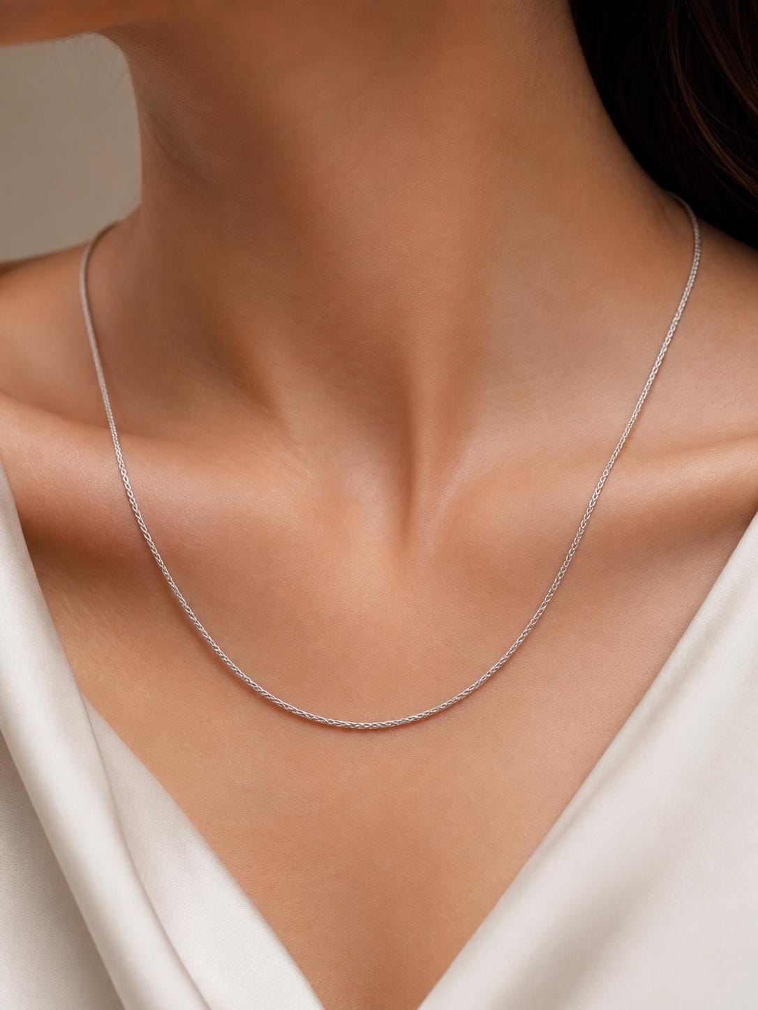 Woman wearing platinum wheat chain necklace with white satin neckline