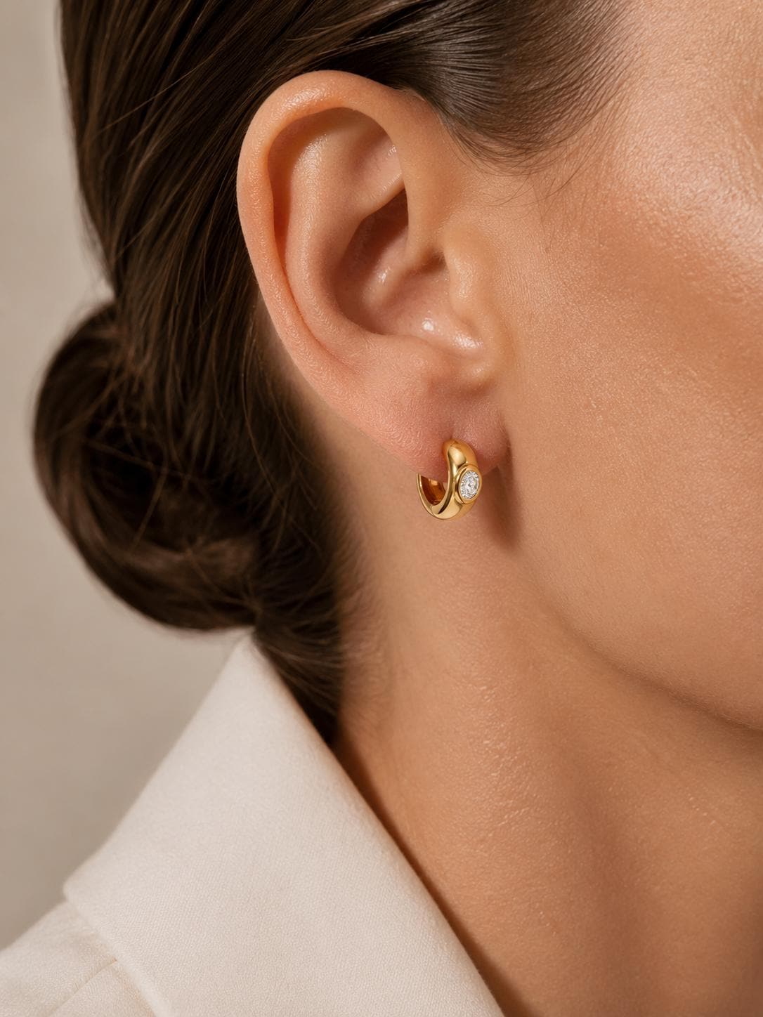 Model wearing chunky 18K gold oval diamond huggie hoops