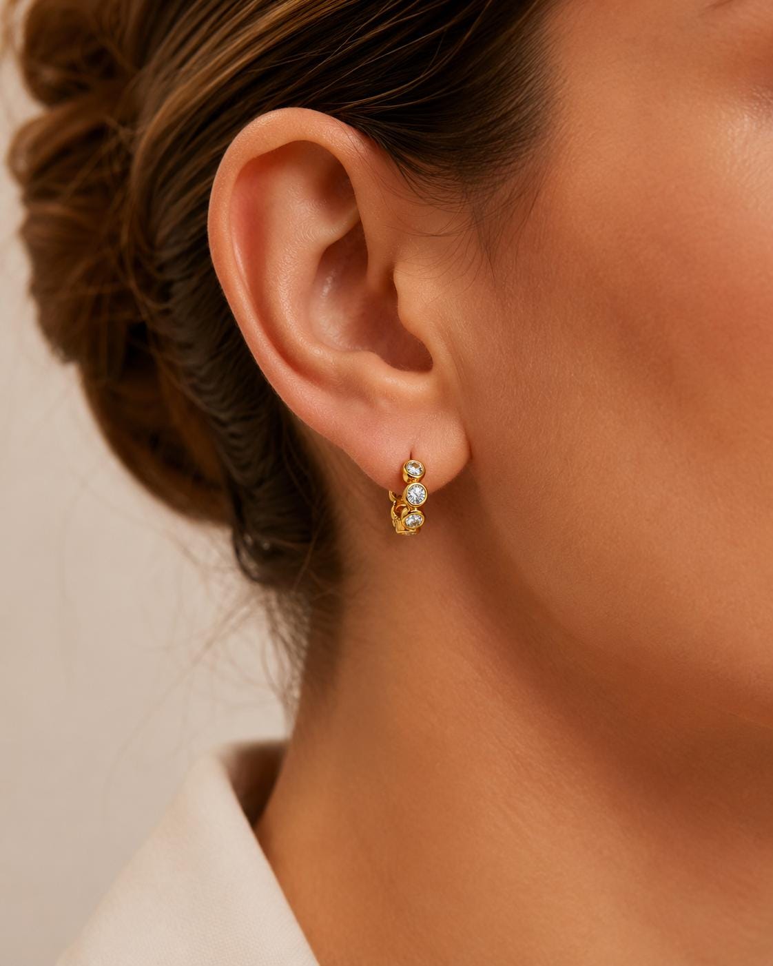 Model wearing 18K gold bezel-set lab diamond huggie earrings