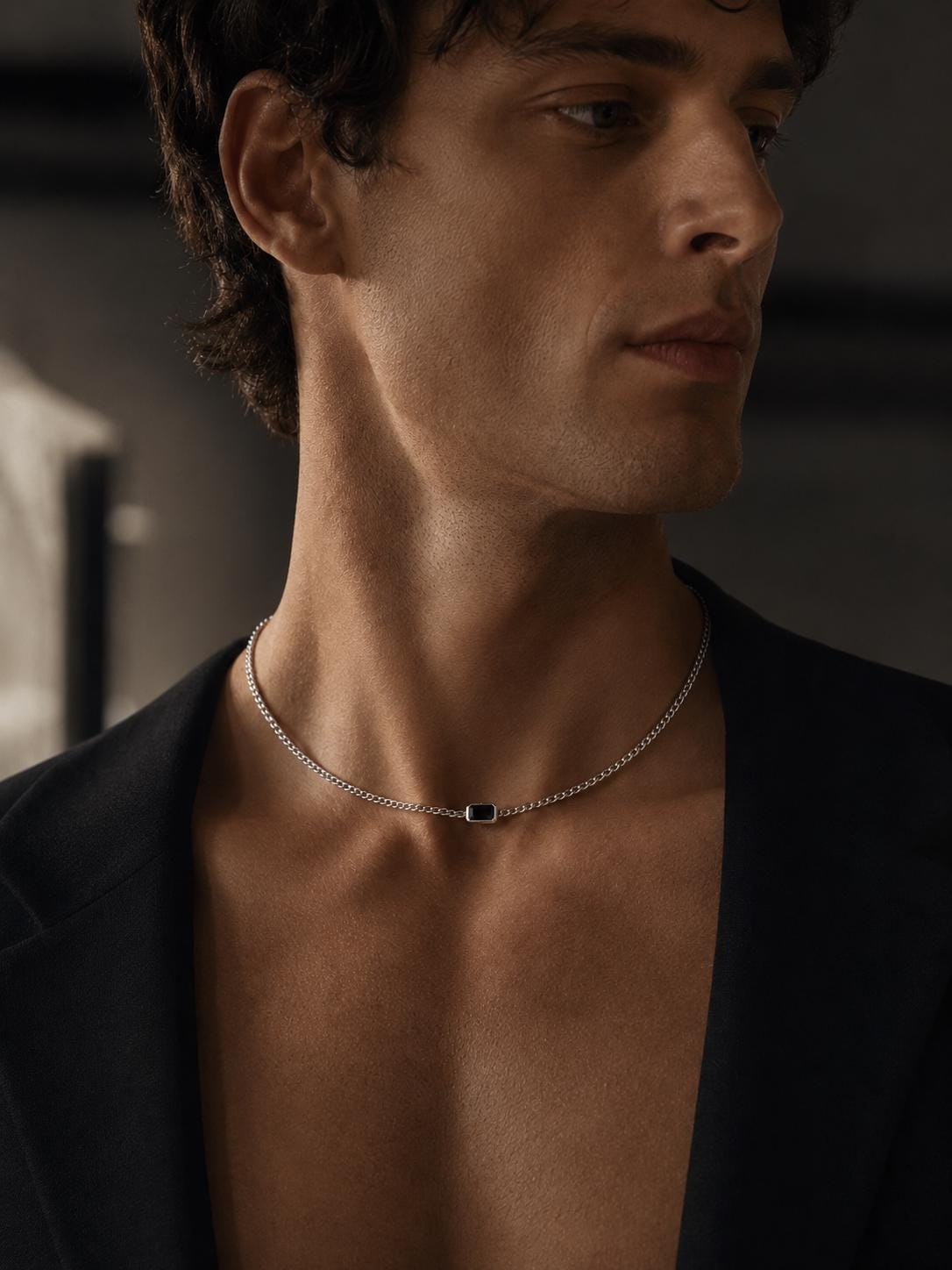 Man wearing black onyx platinum curb necklace with a dark blazer