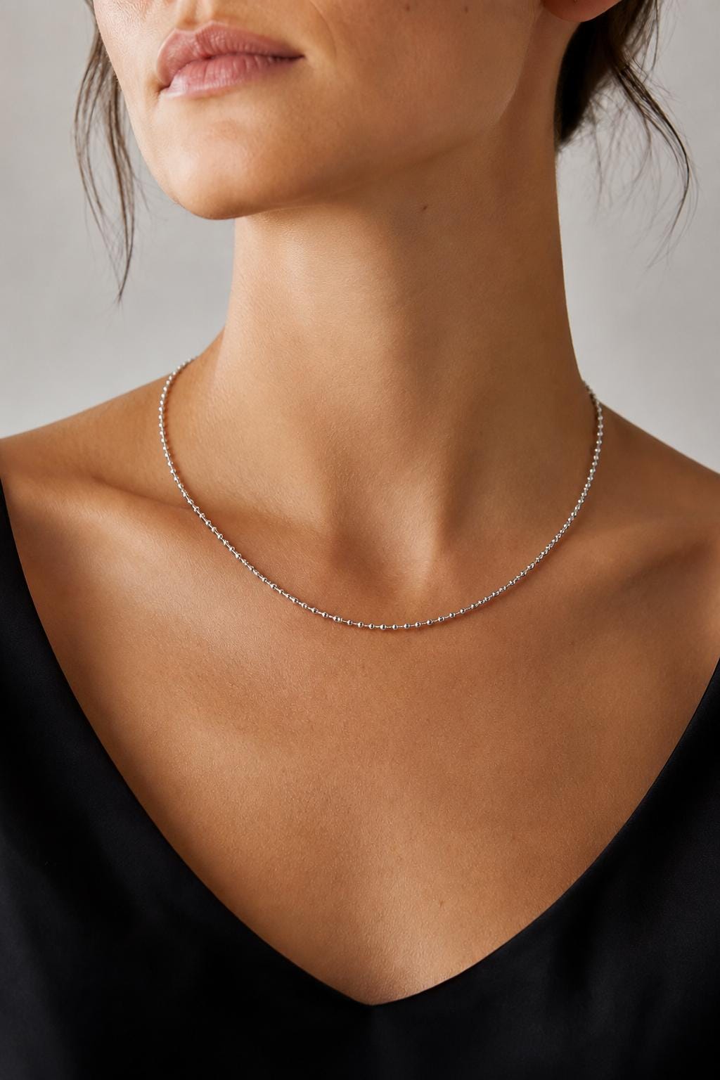 Woman wearing PT950 diamond-cut bead chain with black V-neck
