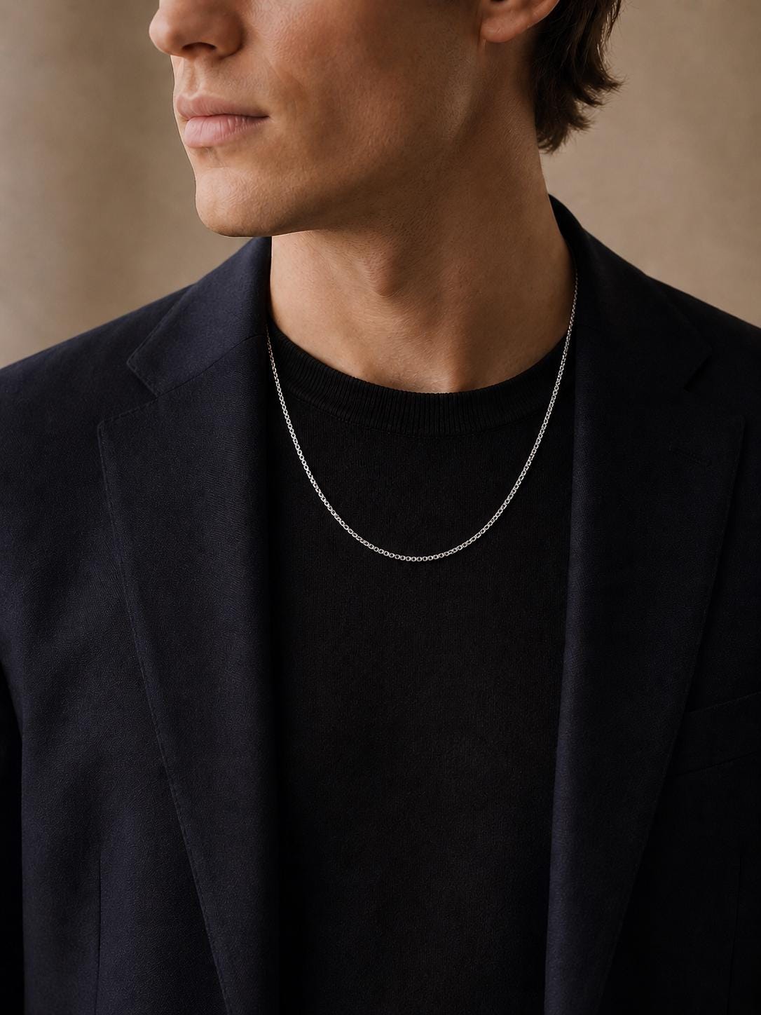 Man wearing solid platinum box chain with navy blazer and black top