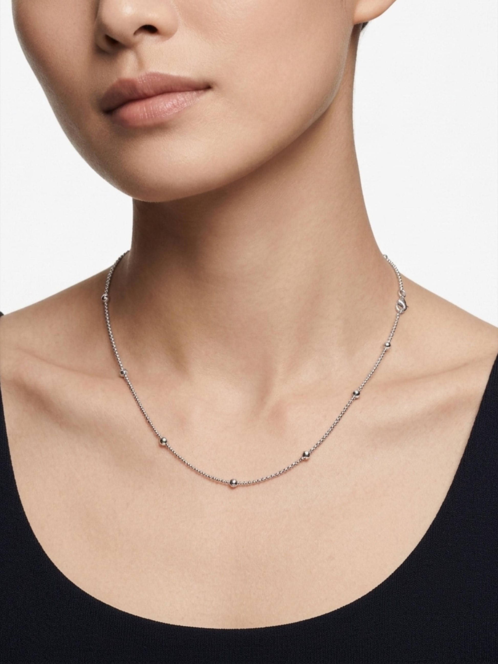 Woman wearing PT950 platinum station necklace with black scoop neckline