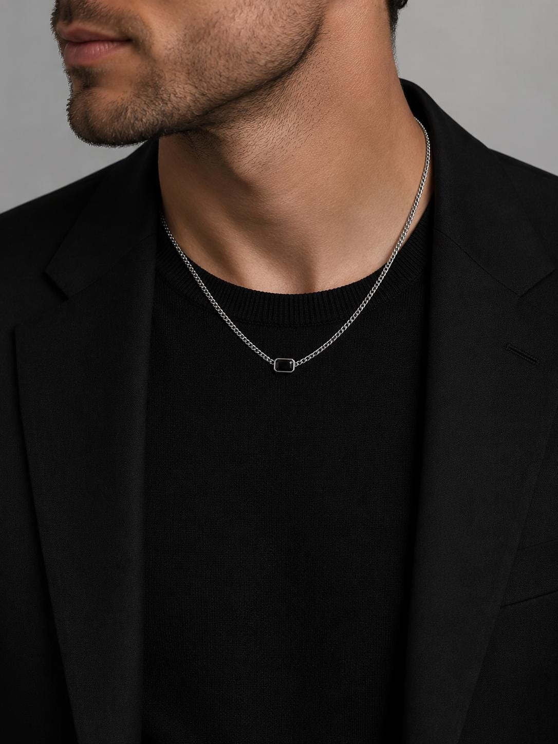 Man wearing PT950 black onyx necklace with black blazer and knitwear