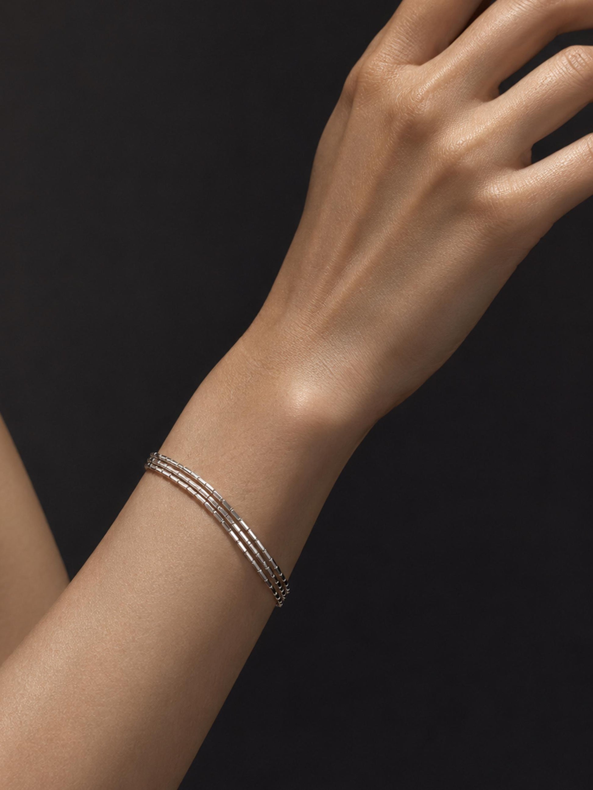 Woman wearing three-strand faceted platinum bracelet