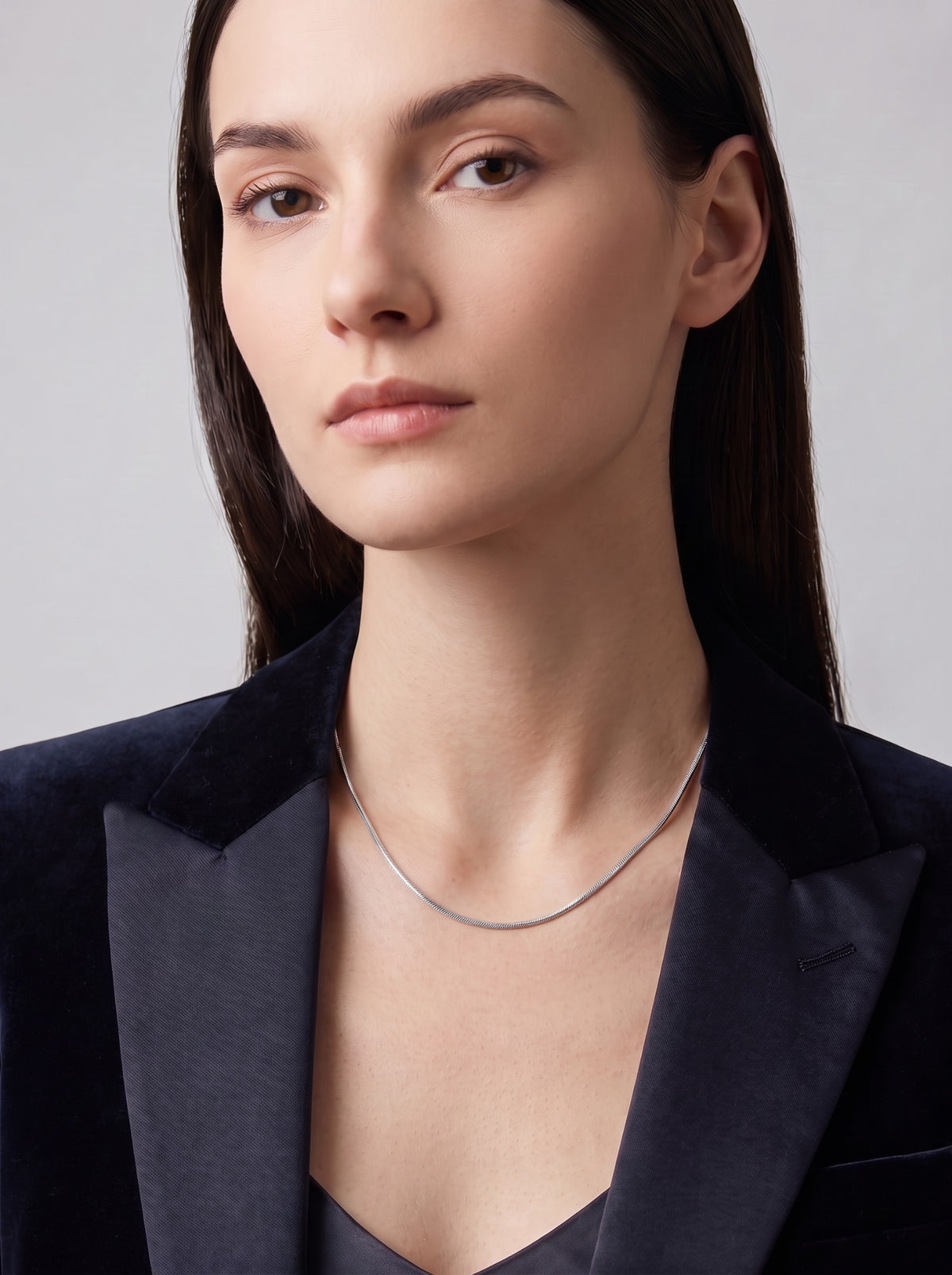 HELIOR Linea Bold platinum snake chain necklace worn with a structured navy blazer.