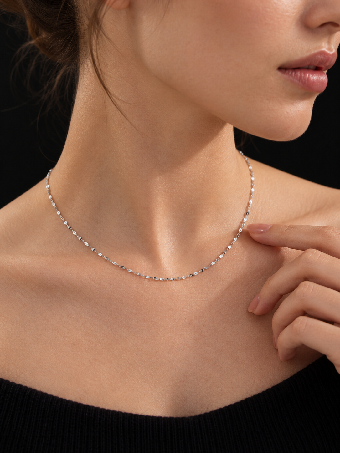 Lustre 1.5mm platinum necklace worn against a black background with a hand showing scale
