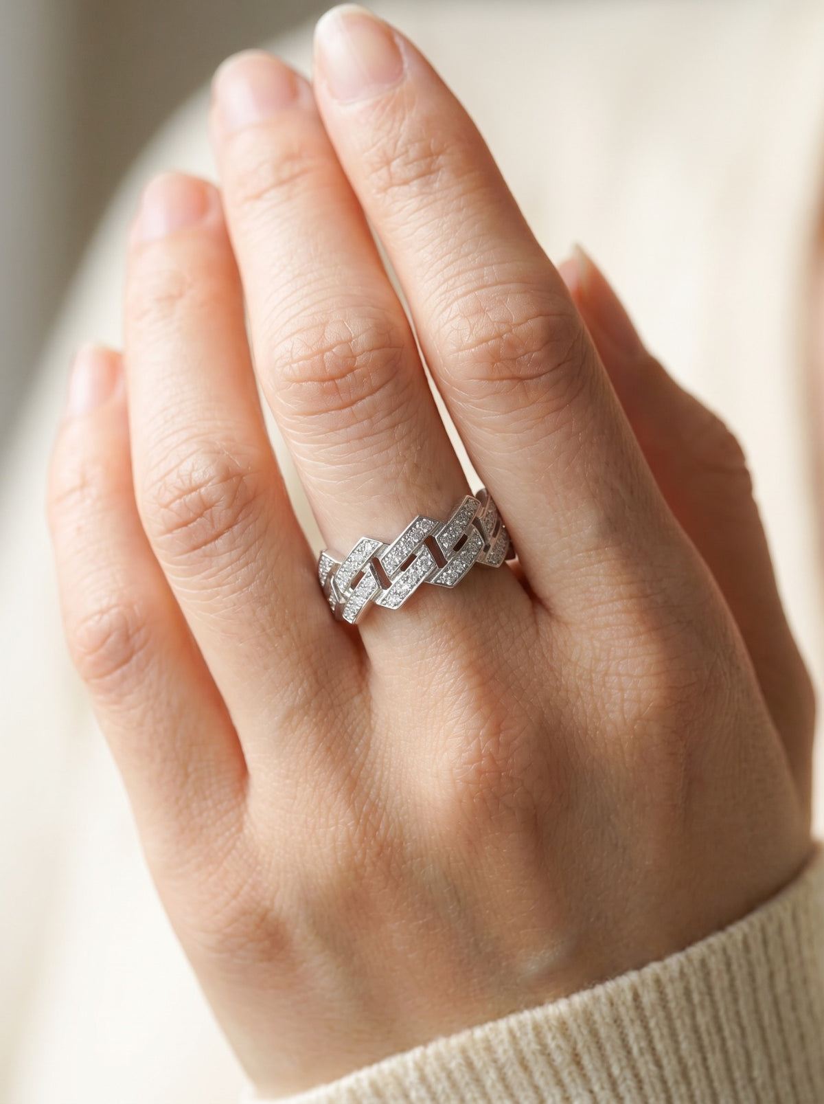 Nexus platinum pavé diamond ring worn against a light knit sleeve.